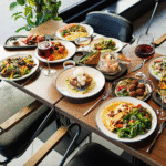 Assorted current and green eating place serving supplies arranged on a wooden desk.